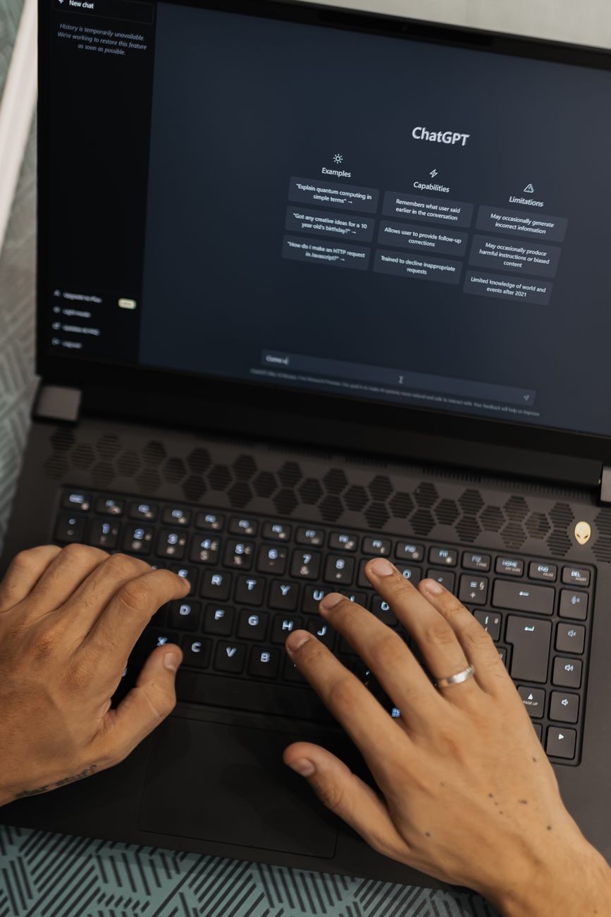 Person typing on a laptop using AI tools including ChatGPT, Gemini, and Claude