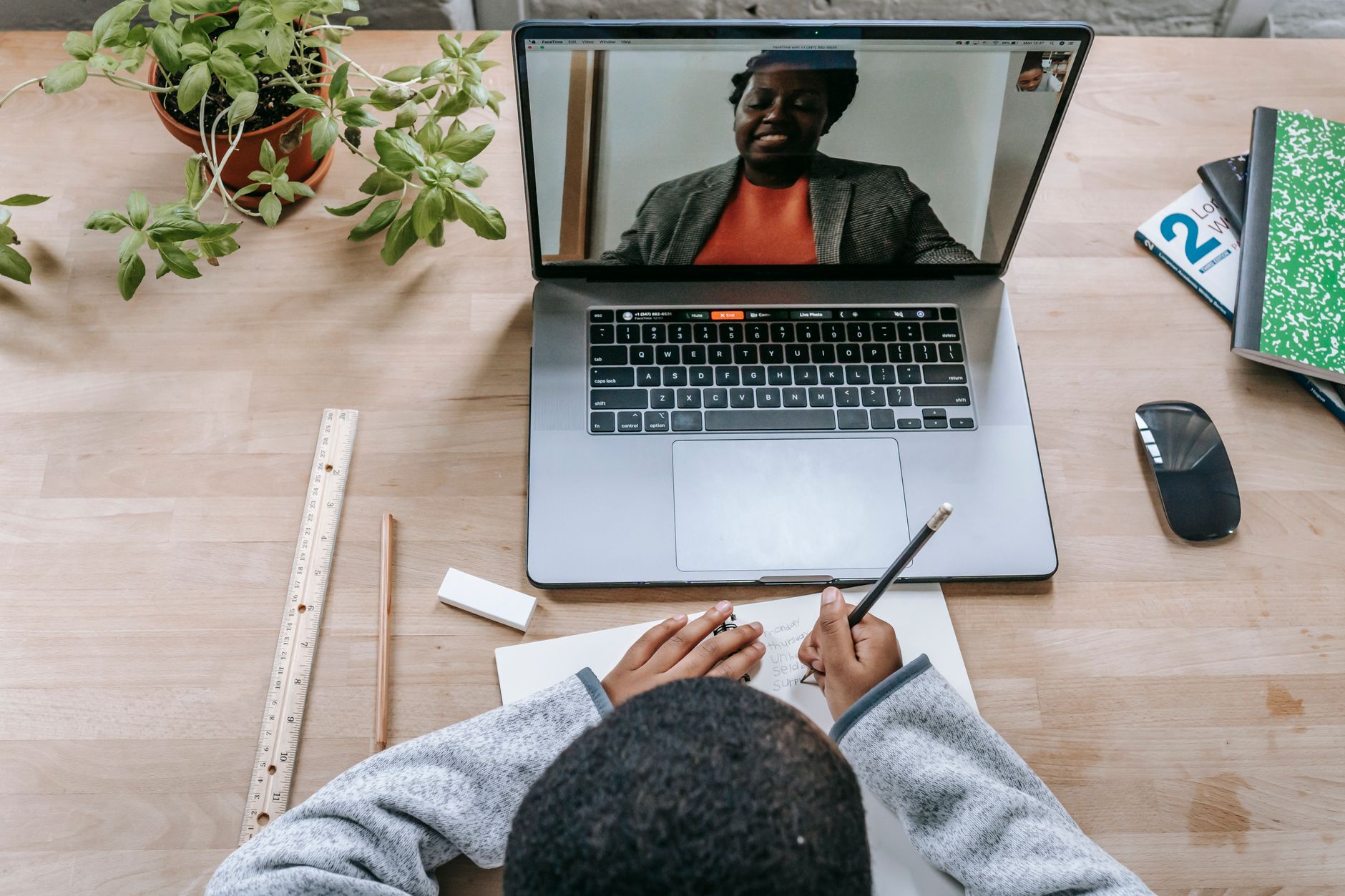 Person learning online at a laptop and taking notes during a free AI course