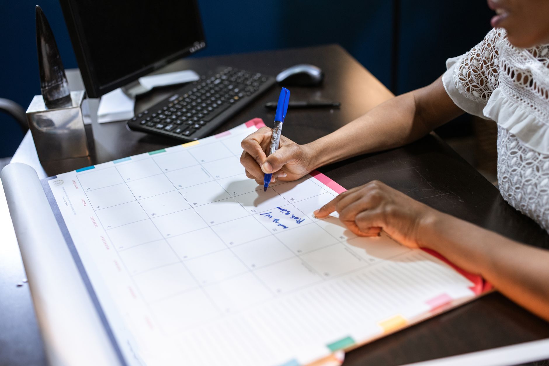 Person planning their day in a daily planner beside a keyboard, illustrating AI for time management