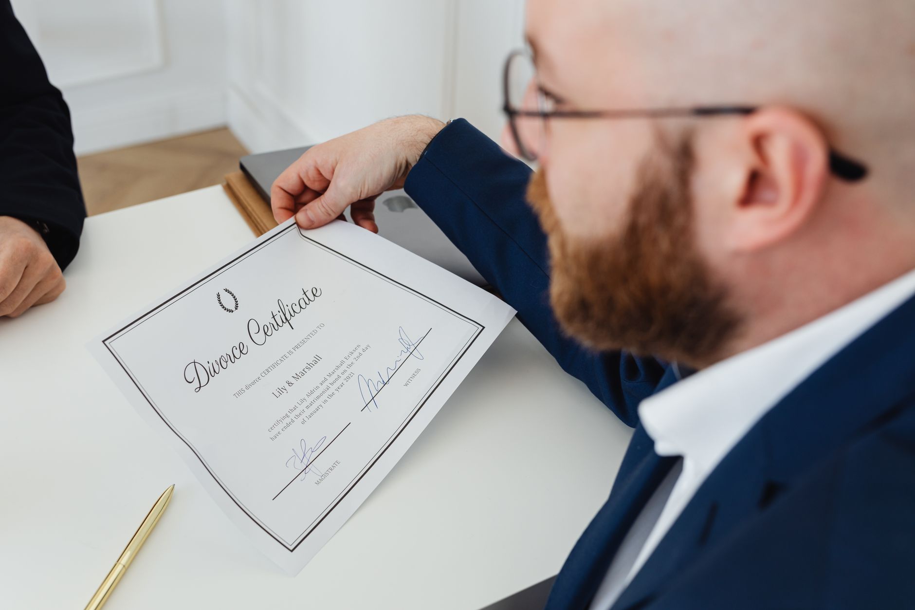 man in blue suit holding a divorce certificate