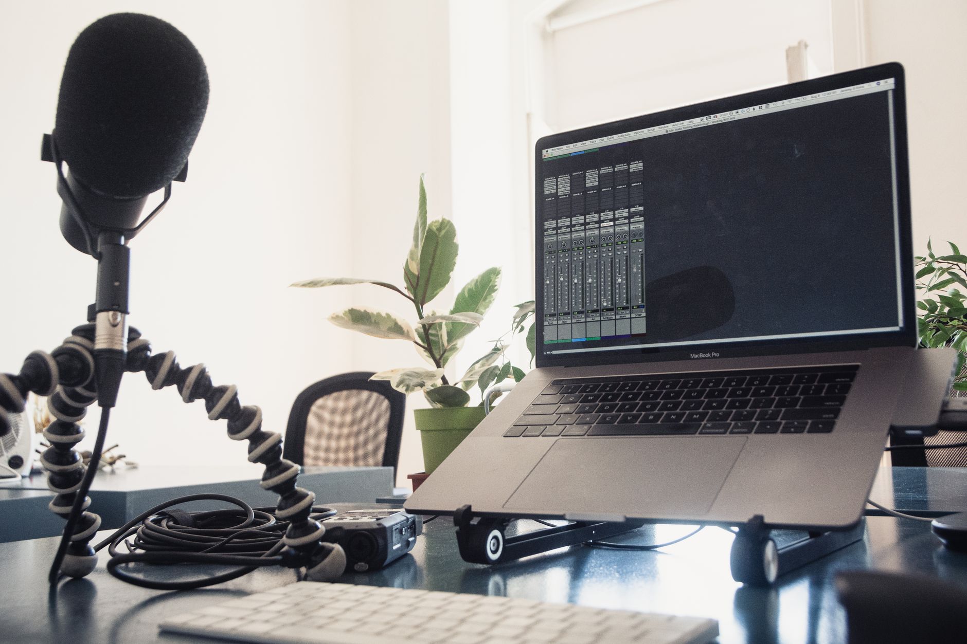 Microphone and headphones next to a laptop on a bright desk, showing AI transcription tools turning audio into text.