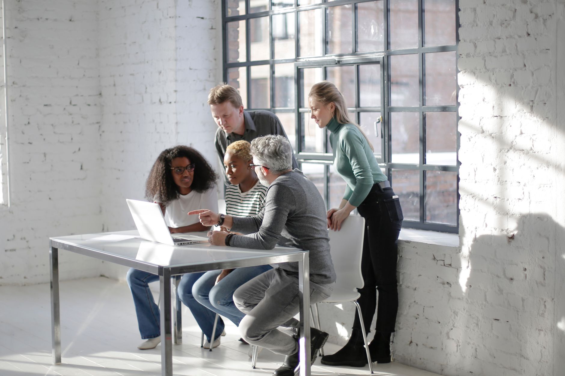 Team collaborating around laptops in a bright modern office, building AI tools